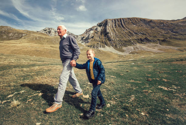 istock Grandfather with grandson walks on mountain road 874015866