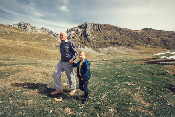 Grandfather with grandson walks on mountain road Grandfather with grandson walks on mountain road durmitor national park photos stock pictures, royalty-free photos & images