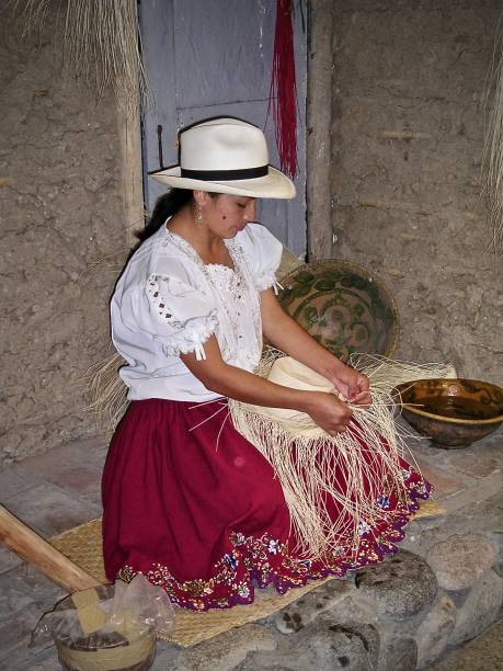 Panama Hat Weaver - Ecuadorian Marketplace 23rd September 2003, Ecuadorian countryside.  A Panama hat weaver in traditional Ecuadorian dress, sits at her pavement stall weaving a new Panama hat in a small town's busy marketplace.   mcdermp stock pictures, royalty-free photos & images