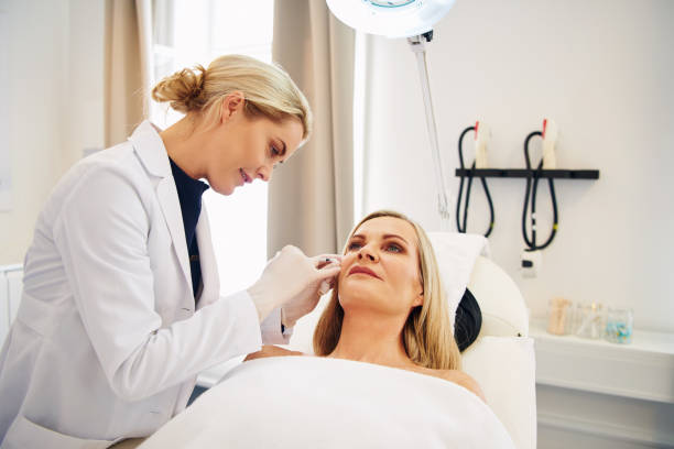 Doctor doing botox injections on a mature client's face Young female doctor doing botox injections on the face of a mature woman lying on a table in a beauty clinic dermatology stock pictures, royalty-free photos & images