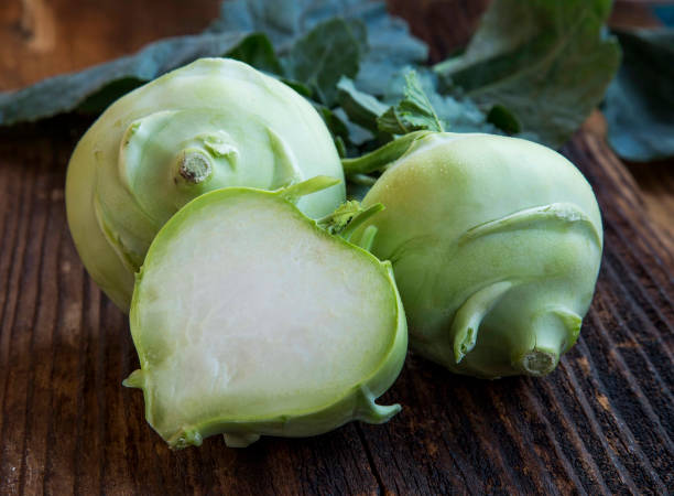 interi vegetali di radice di kohlrabi freschi biologici e mezzo su un tavolo di legno - kohlrabi turnip kohlrabies cabbage foto e immagini stock