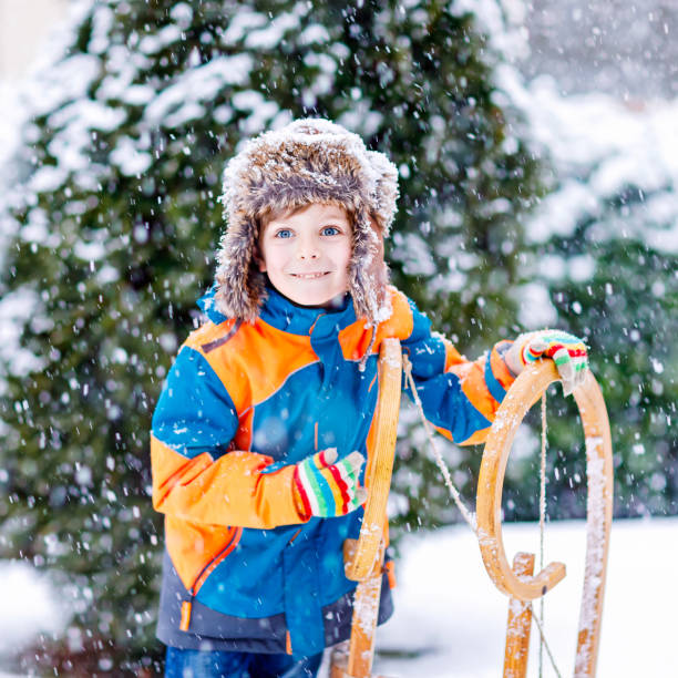 kleine kind junge schlittenfahrt im winter zu genießen - little boys sled clothing slide stock-fotos und bilder