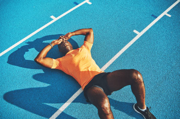 Exhausted young athletic lying on a running track after training