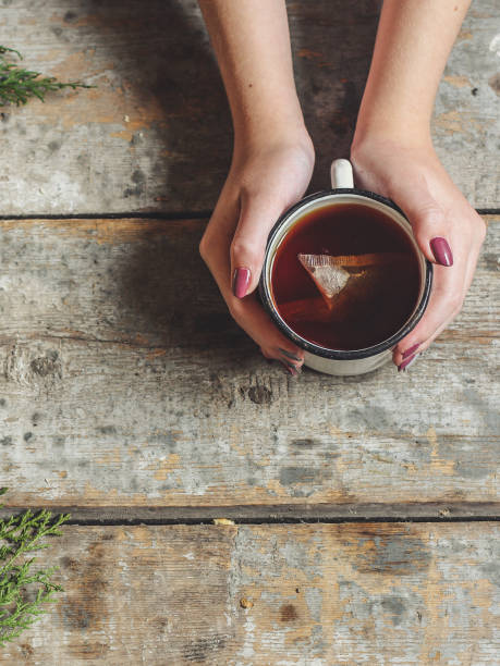 istock background - tea, holding a cup on a wooden background and a green branch 874030986