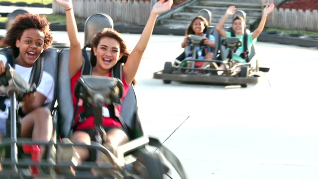Teenagers riding go-carts at amusement park