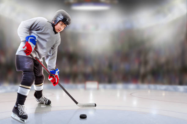 Junior Hockey Player Puck Handling in Arena Low angle view of hockey player handling puck on ice with sports arena full of fans in the stands and copy space. Shallow depth of field on background. hockey online bookies site stock pictures, royalty-free photos & images
