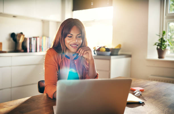 istock Smiling young female entrepreneur working online at her kitchen table 874046156