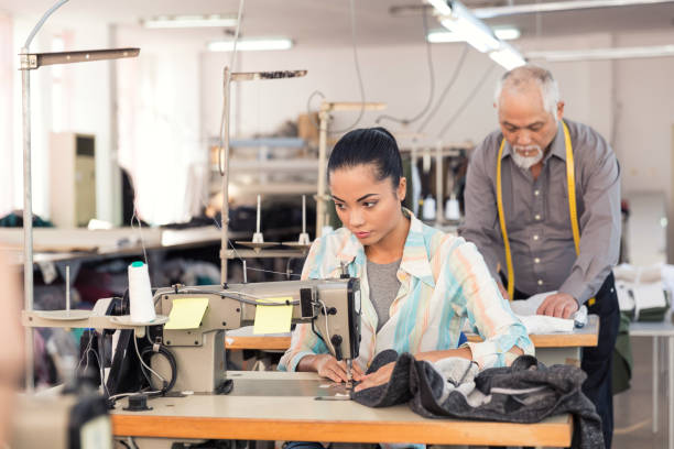 istock Young woman sewing in textile factory 874046980