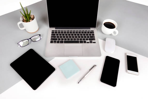 istock Flat lay photo of Office table with laptop computer, notebook, digital tablet, mobile phone, Pencil, eyeglasses  on modern two tone (white and grey) background. Desktop office mockup concept. 874047462