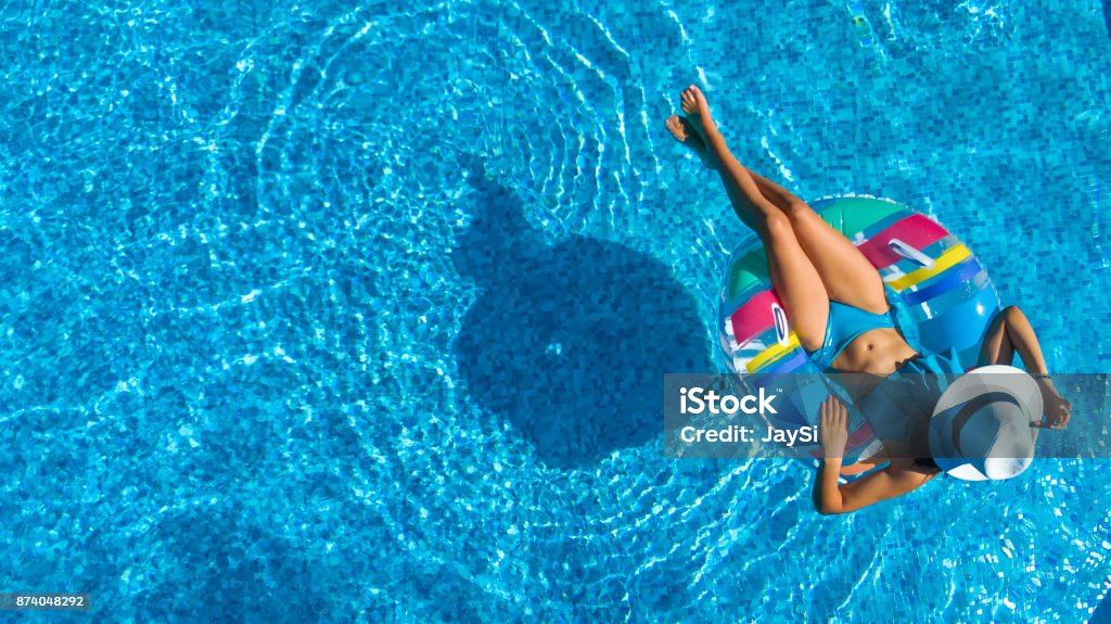 Vista aerea della bellissima ragazza in piscina dall'alto, rilassati a nuotare sulla ciambella gonfiabile e divertiti in acqua durante le vacanze in famiglia - Foto stock royalty-free di Famiglia