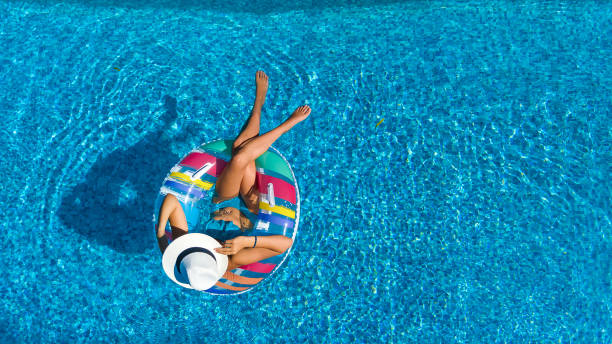 Aerial top view of beautiful girl in swimming pool from above, relax swim on inflatable ring donut and has fun in water on family vacation Aerial top view of beautiful girl in swimming pool from above, relax swim on inflatable ring donut and has fun in water on family vacation inner tube stock pictures, royalty-free photos & images