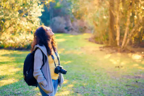 Woman with curly hair wearing glasses admiring the landscape and the beauties of nature - Photographer's day.