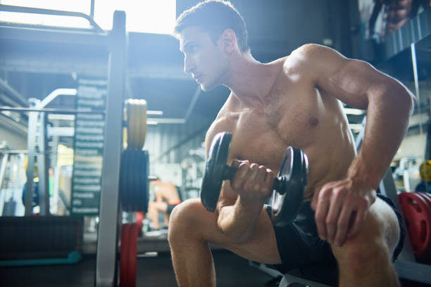 istock Handsome Man Pumping Arm Muscles in Gym 874062644