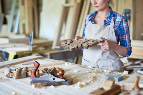 istock Female Carpenter Carving Wooden Part in Workshop 874066994