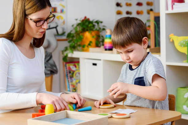 istock Kindergarten Teacher and Cute Boy Playing Educational Games in Classroom 874067168