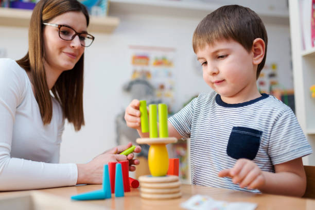 istock Kindergarten Teacher and Cute Boy Playing Educational Games in Classroom 874070960