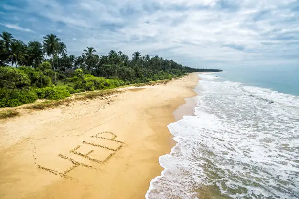 Uninhabited and wild tropical island with a deserted beach. Sand with the inscription HELP.