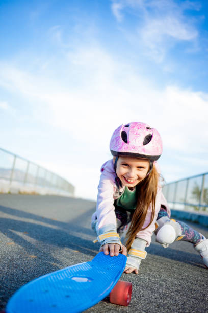 istock Girl in Protective Gear Grabbing for Skateboard 874092460
