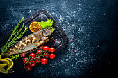 Trout fish baked with aromatic herbs and spices. On Wooden background.