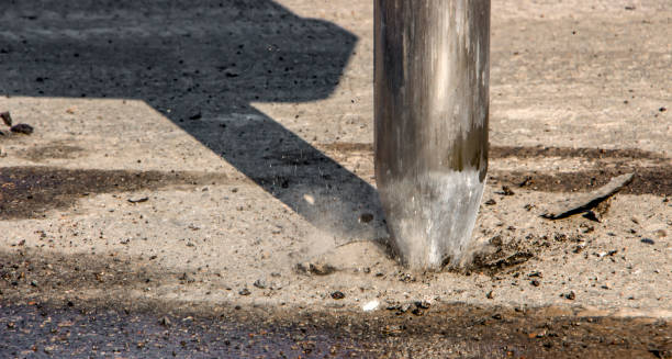 istock Excavator breaking and drilling the concrete road for repairing 874097710