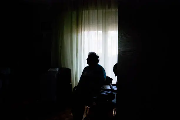 Photo of Senior Woman Alone in Dark Room