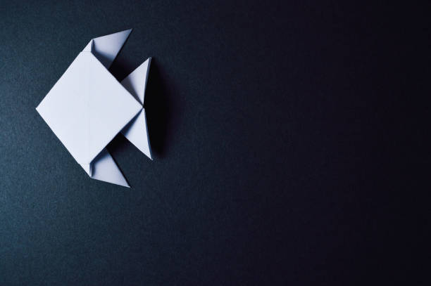 istock origami fish on dark background 874103674