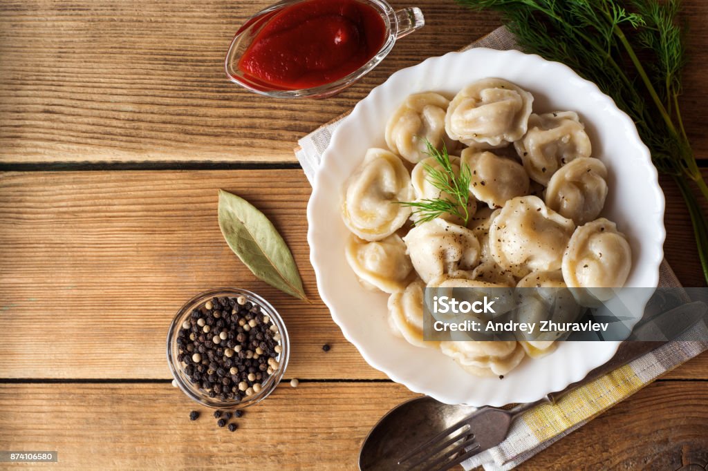 Russian meat dumplings pelmeni with dill on wooden rustic background. Russian meat dumplings pelmeni with dill on wooden rustic background. Top view. Copy space. Russia Stock Photo