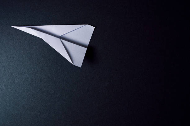 istock origami plane on dark background pointing to left 874110468
