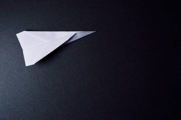 istock origami plane on dark background pointing to right 874110692