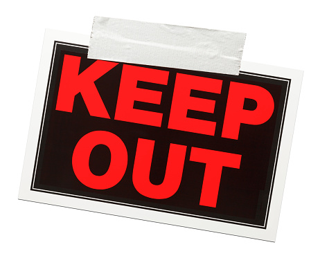 Red and black keep out sign with tape holding it up isolated on a white background.