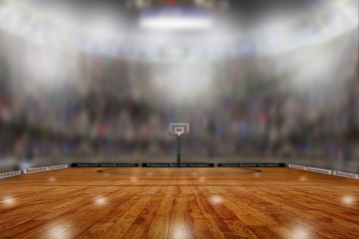 Low angle view of fictitious basketball arena with sports fans in the stands. Focus on foreground with deliberate shallow depth of field on background and copy space.