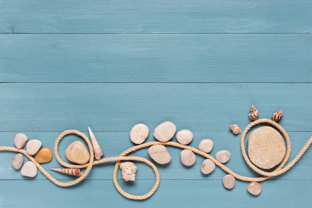 istock Blue wooden background decorated with rope, pebble and shells 874139928