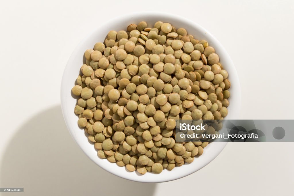 Lens culinaris is scientific name of Lentil legume. Also known as Lentilha Canadense (portuguese) or Lentejas (spanish). Top view of grains in a bowl. White background. Lentil Stock Photo