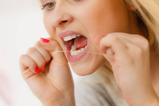 istock Woman cleaning her teeth using dental floss 874153940