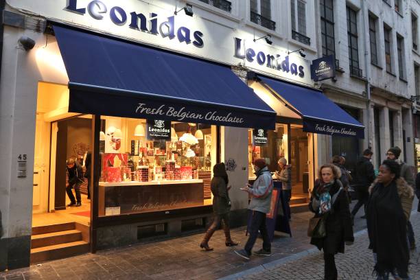 Belgium chocolate store Brussels: People walk by Belgian chocolate store Leonidas in Brussels. There are over 2,000 chocolatiers in Belgium. old candy store stock pictures, royalty-free photos & images