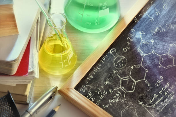 istock Classroom desk and drawn blackboard of chemistry teaching elevated view 874157646