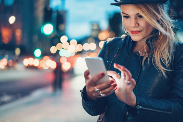 istock Beautiful girl with smart phone outdoors at night 874160428