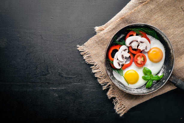 istock Fried egg with herbs and vegetables in a frying pan. Top view. Free space. 874164744