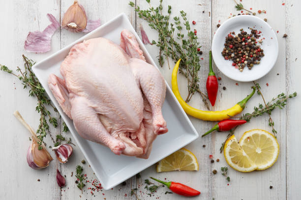 Raw chicken, herbs and spices on white wooden background