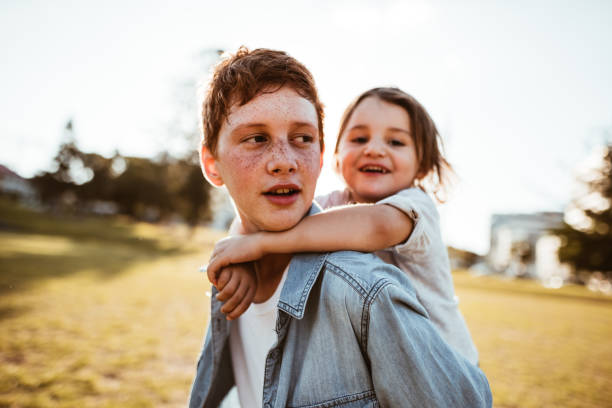 two lovely kids piggyback at the park