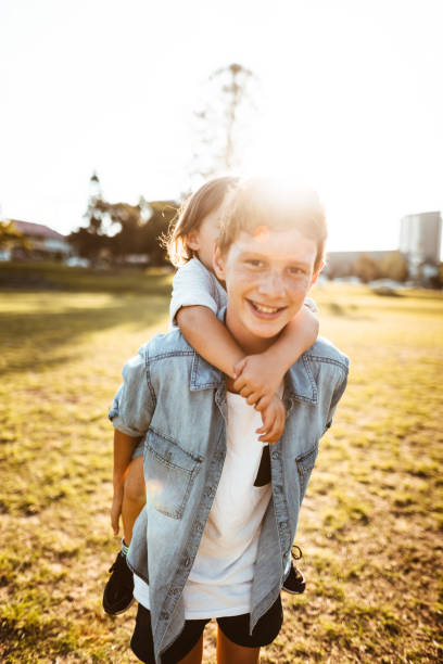 istock two lovely kids piggyback at the park 874176366