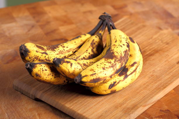 tas de bananes trop mûrs sur un fond en bois - à maturité photos et images de collection