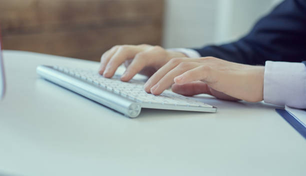 istock Close up of male hands typing on desktop computer keyboard in office. 874193568