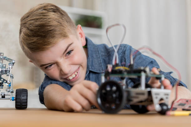istock Cheerful tween boy smiles while building a robotic vehicle 874205282