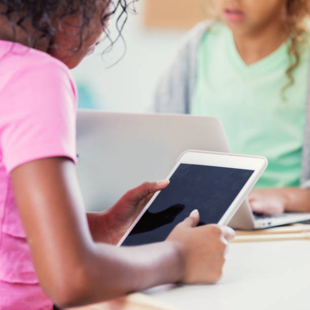 istock Schoolgirl uses digital tablet in classroom 874205674