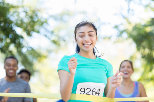 istock Excited young female runner crosses finish line 874205894