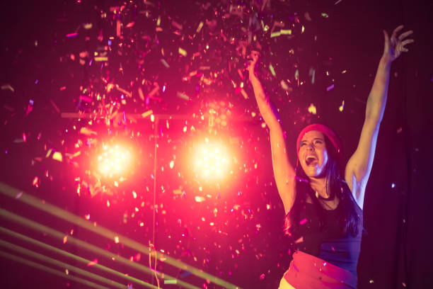 istock Happy woman dancing under confetti at a party 874222328