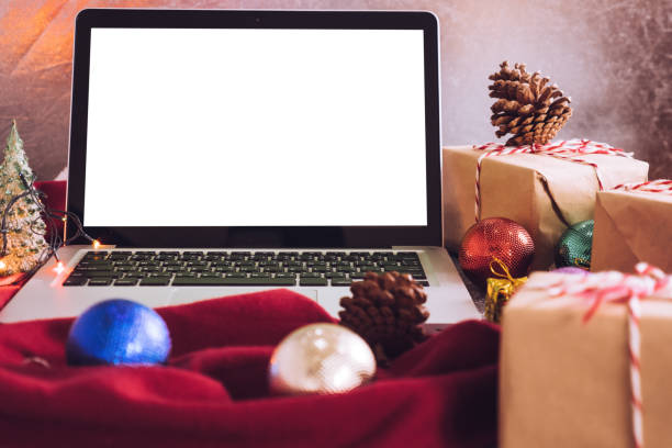 istock Laptop with white screen, gift boxes and christmas decoration on the table. 874222366