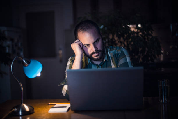 istock Young man working on laptop late night from home 874228296