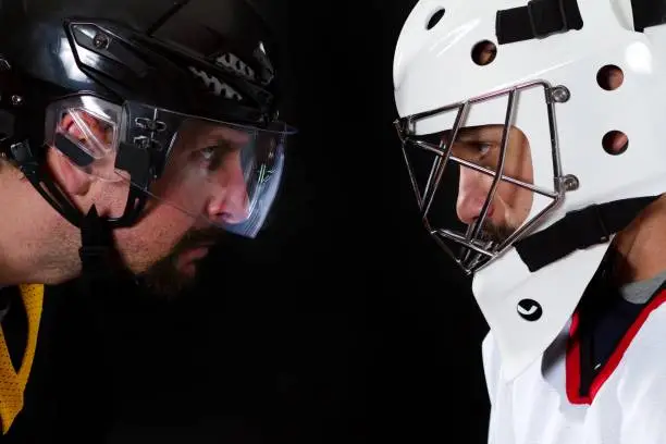 A hockey player staring down a hockey goalie.
